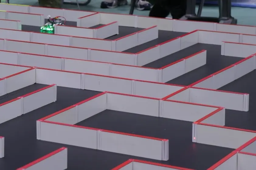 Un robot Micromouse dentro del laberinto de paredes blancas con borde rojo
